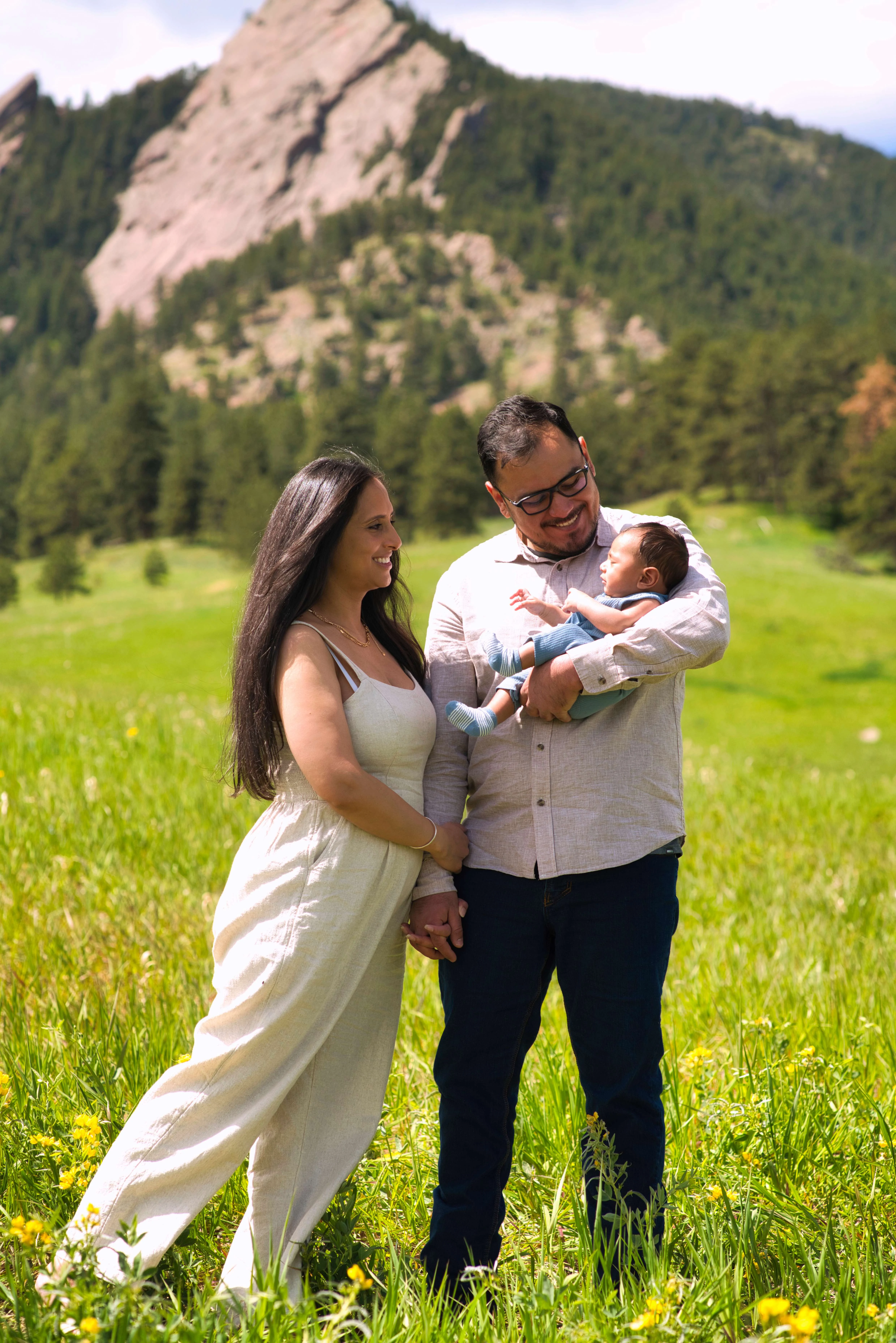 Boulder Family Photography with Flatirons Mountain Backdrop Couple holding baby in front of the Flatirons mountains, Boulder family photography