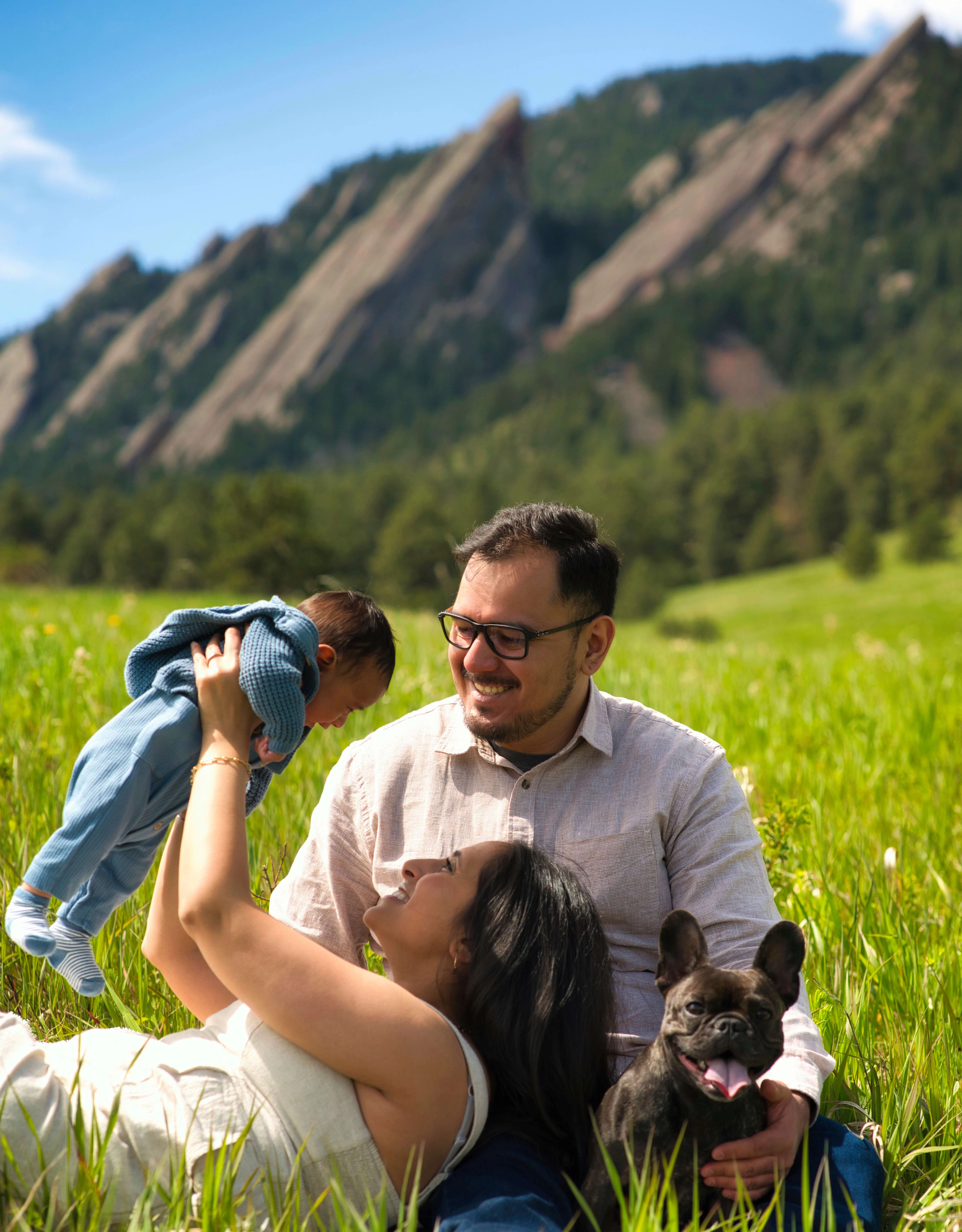 Denver Family Photographer – Newborn and Family Session Family lifting baby in the air with dog in grassy field near the Flatirons, Boulder, Colorado