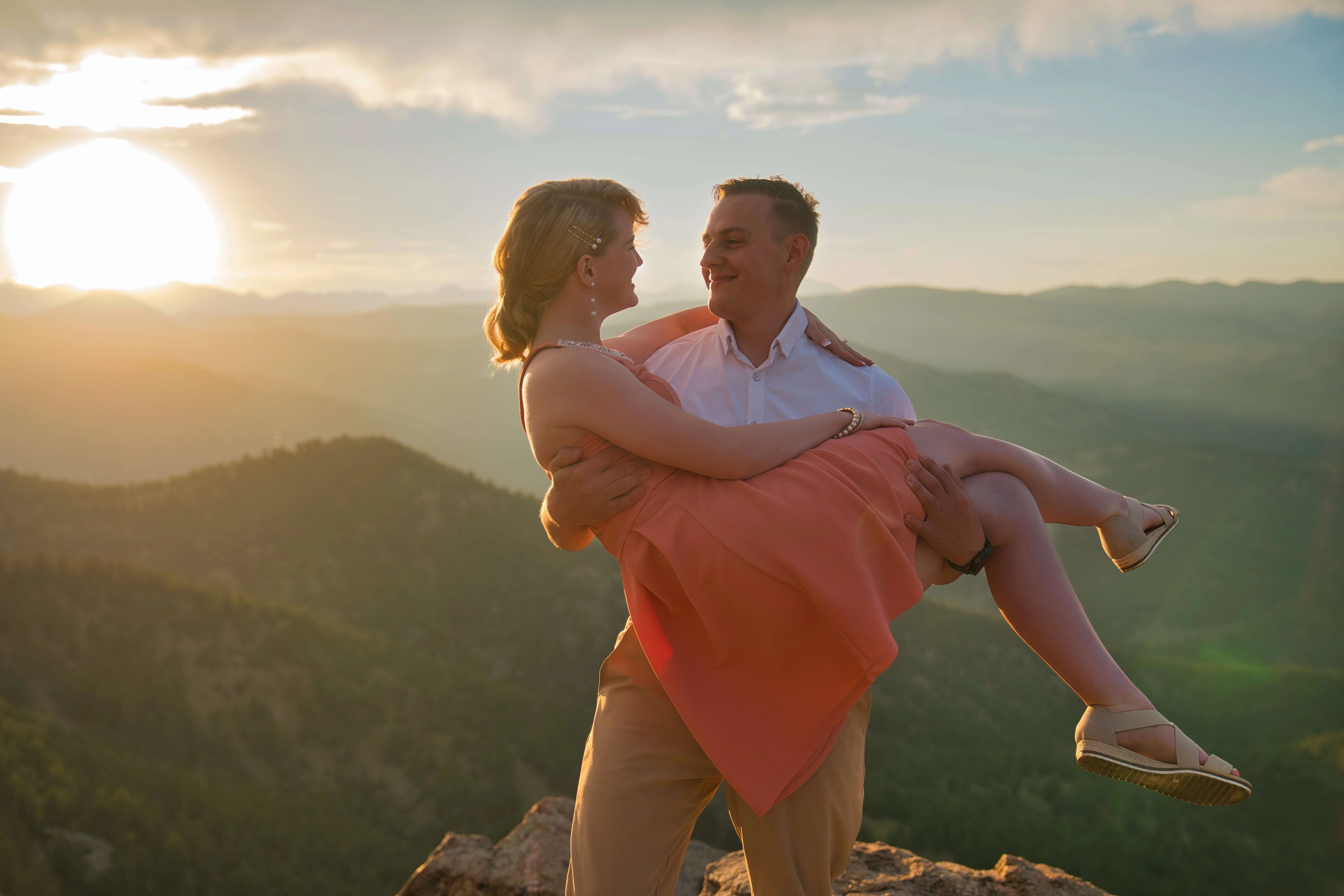 Groom-to-be carrying fiancée at sunset mountain overlook, Denver engagement photography